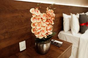 a vase with flowers on a table in a hotel room at Roma Hotel by H Hotéis - Airport in Brasília