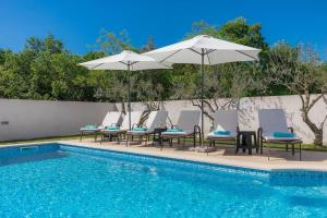 a group of chairs and umbrellas next to a pool at Villa Prisedi in Rakalj