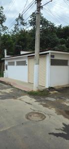 a white building with two garage doors and a pole at Casa BNH in Cachoeiro de Itapemirim