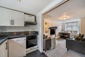 a kitchen with white cabinets and a living room at Quarter Deck in Ulverston