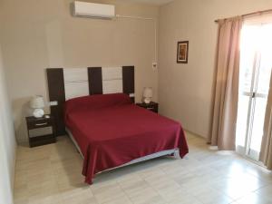 a bedroom with a bed with a red bedspread at Hermoso Departamento en Quines in Quines