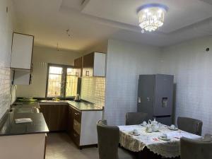 a kitchen with a table with chairs and a refrigerator at De Royal Lodge in Abaranjeh