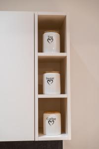 a white cupboard with twoerrederrederred coffee cups at Apartman Dunja Zepterme in Vrnjačka Banja
