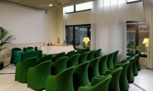 a row of green chairs in a room with a table at Phi Hotel Emilia in Ozzano dell'Emilia