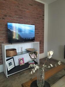 a living room with a television on a brick wall at Relax MDZ - Memorable Apt in Godoy Cruz