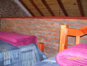 波特雷罗德洛斯弗内斯Pauvalén Cabañas的有两张床和一堵砖墙的房间
