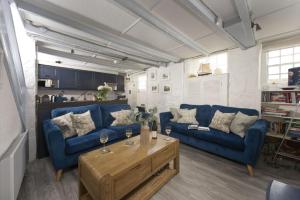 a living room with blue couches and a coffee table at Mariners Cottage, St Ives in St Ives