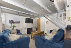 a living room with two blue couches and a fireplace at Mariners Cottage, St Ives in St Ives