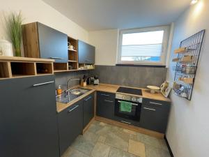 een keuken met zwarte kasten, een gootsteen en een raam bij Ferienwohnung in ländlicher Idylle in Meschede