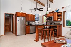 a kitchen with wooden cabinets and a stainless steel refrigerator at Residences at Barrier Reef Casita 4 by Stay Floreo in San Pedro