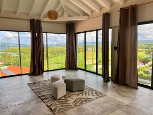 a room with large windows with a chair and a rug at Villa passion vanille in Les Trois-Îlets