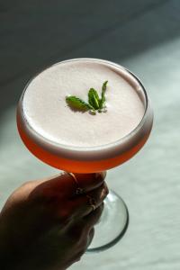a person holding up a drink with a mint garnishment at Aloft London Excel in London