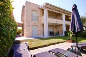 einen Regenschirm und Stühle vor einem Gebäude in der Unterkunft Villetta Rovizza in San Martino della Battaglia
