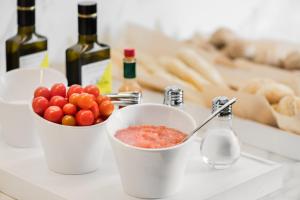 einen Tisch mit einer Schüssel Tomaten und Weinflaschen in der Unterkunft AC Hotel by Marriott Alicante in Alicante