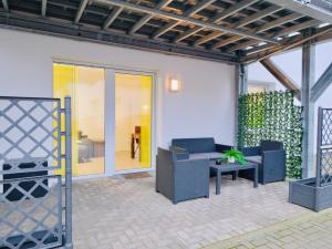 a patio with chairs and a couch and a table at Fine Living - Zentral, barrierefrei mit Terrasse & 24h Parkhaus in Nähe in Peine