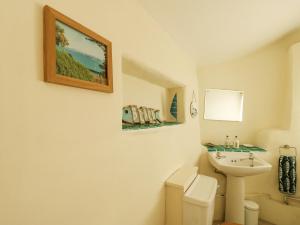 a white bathroom with a sink and a toilet at Bryn Teg Cottage in Moelfre +23 photos