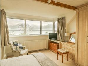 a bedroom with a bed and a television and a chair at Bryn Teg Cottage in Moelfre