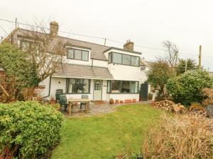 a house with a picnic table in the yard at Bryn Teg Cottage in Moelfre