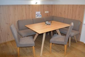 a table with four chairs and a wooden table with a bowl on it at Gästehaus Huber in Leogang