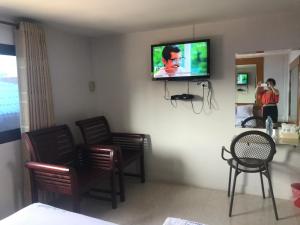 a living room with a tv on a wall with chairs at ใสเจริญรีสอร์ท in Ban Yuan Lae