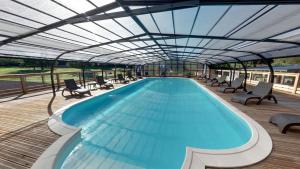 a large swimming pool with chairs and a roof at Camping Les Vernieres La Bourboule Sancy in La Bourboule