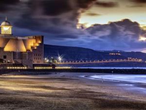 ein Gebäude mit einem Leuchtturm am Strand in der Nacht in der Unterkunft Las Canteras Deluxe in Las Palmas de Gran Canaria
