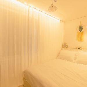a white bedroom with a bed and a curtain at Noddle Sun Stay in Seoul