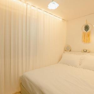a white bedroom with a bed and a curtain at Noddle Sun Stay in Seoul