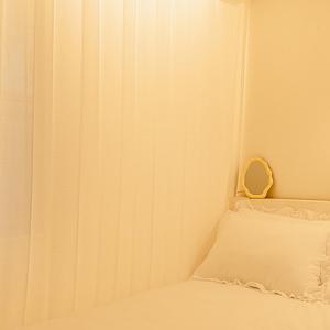 a white bed with a pillow and a curtain at Noddle Sun Stay in Seoul