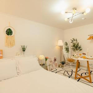 a white bedroom with a bed and a table at Noddle Sun Stay in Seoul