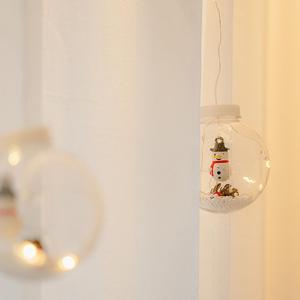 a snowman ornament in a glass jar hanging from a wall at Noddle Sun Stay in Seoul