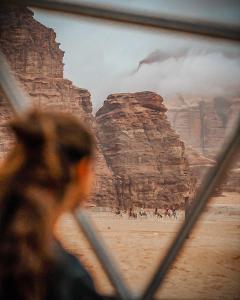 a man looking through a window at a group of people riding horses at Wadi Rum Relaxation Camp in Wadi Rum