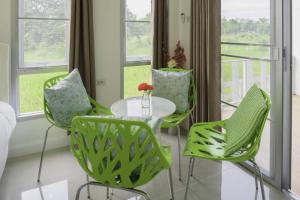 a room with green chairs and a table and windows at Chaisathan Cottage in Ban Ton Chok