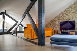 a living room with orange furniture and a tv at L'Artbanne - Maison Gaïa in Saint-Hilaire-le-Petit