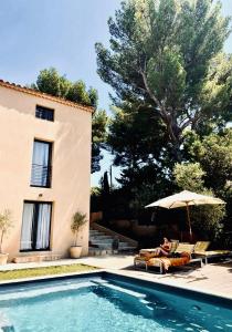 a person sitting on a chair under an umbrella next to a pool at AQUARIUS IN CASSIS, Chambres d'Hôtes in Cassis