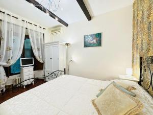 una camera da letto bianca con un letto e una televisione di Via Veneto Lulus Home a Roma