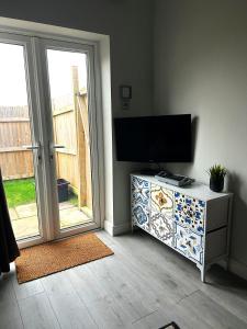a living room with a tv on a dresser next to a door at Nidd House Apartment in Harrogate +3 photos