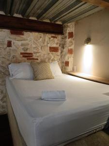 ein großes weißes Bett in einem Zimmer mit einer Steinwand in der Unterkunft Duplex en Getsemani TWON in Cartagena de Indias