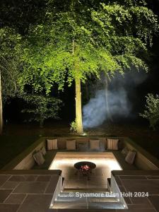un focolare nel mezzo di un giardino di notte di Sycamore Barn a Holt