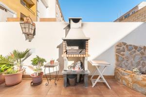 een terras met een houtoven op een witte muur bij Yovalutres Piscina Privada Torrevi in Torrevieja