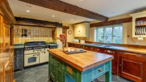 a large kitchen with wooden cabinets and a stove at Coppice House in Ashton under Hill