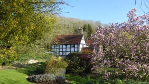 a house in the middle of a garden with flowers at Coppice House in Ashton under Hill