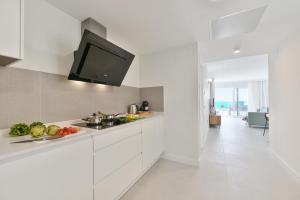 Una cocina con gabinetes blancos y un televisor de pantalla plana. en Balcon Azul IV by VillaGranCanaria, en Telde