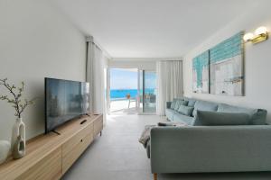Una sala de estar con un sofá azul y un televisor. en Balcon Azul IV by VillaGranCanaria, en Telde