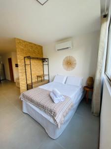 a bedroom with a large white bed with towels on it at Lindo Apartamento em condomínio de frente para o mar - Villa Naluri B107 in Japaratinga