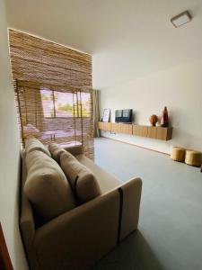 a living room with a couch and a large window at Lindo Apartamento em condomínio de frente para o mar - Villa Naluri B107 in Japaratinga