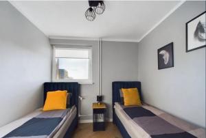 two beds with yellow pillows in a room at AM apartments 6 Szczecin City Center Wyzwolenia in Szczecin