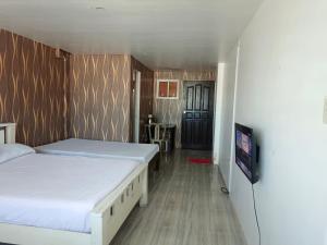 a bedroom with two beds and a tv in it at Montecarlo Townhouse Residences II in Cangbaliguia +16 photos