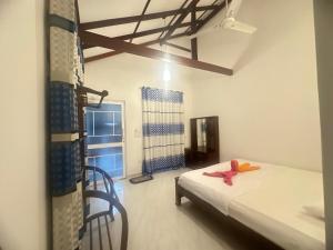 Un dormitorio con una cama y una silla y una ventana. en Mirissa Diamond Beach Villa, en Mirissa