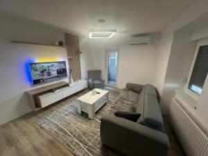 APARTMAN DBR -Dobrinja Sarajevo-FREE GARAGE في سراييفو: غرفة معيشة مع أريكة وتلفزيون